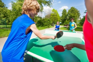 Kinder spielen Tischtennis im Garten
